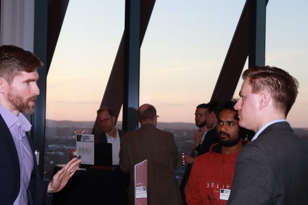 Chris from Groma talking with members at a BBA rooftop event at sunset